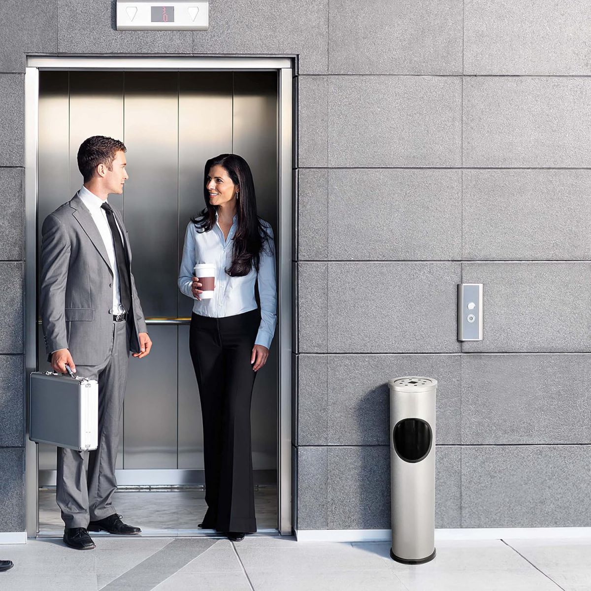 Business professionals standing in an elevator near a stainless steel outdoor dust rubbish bin