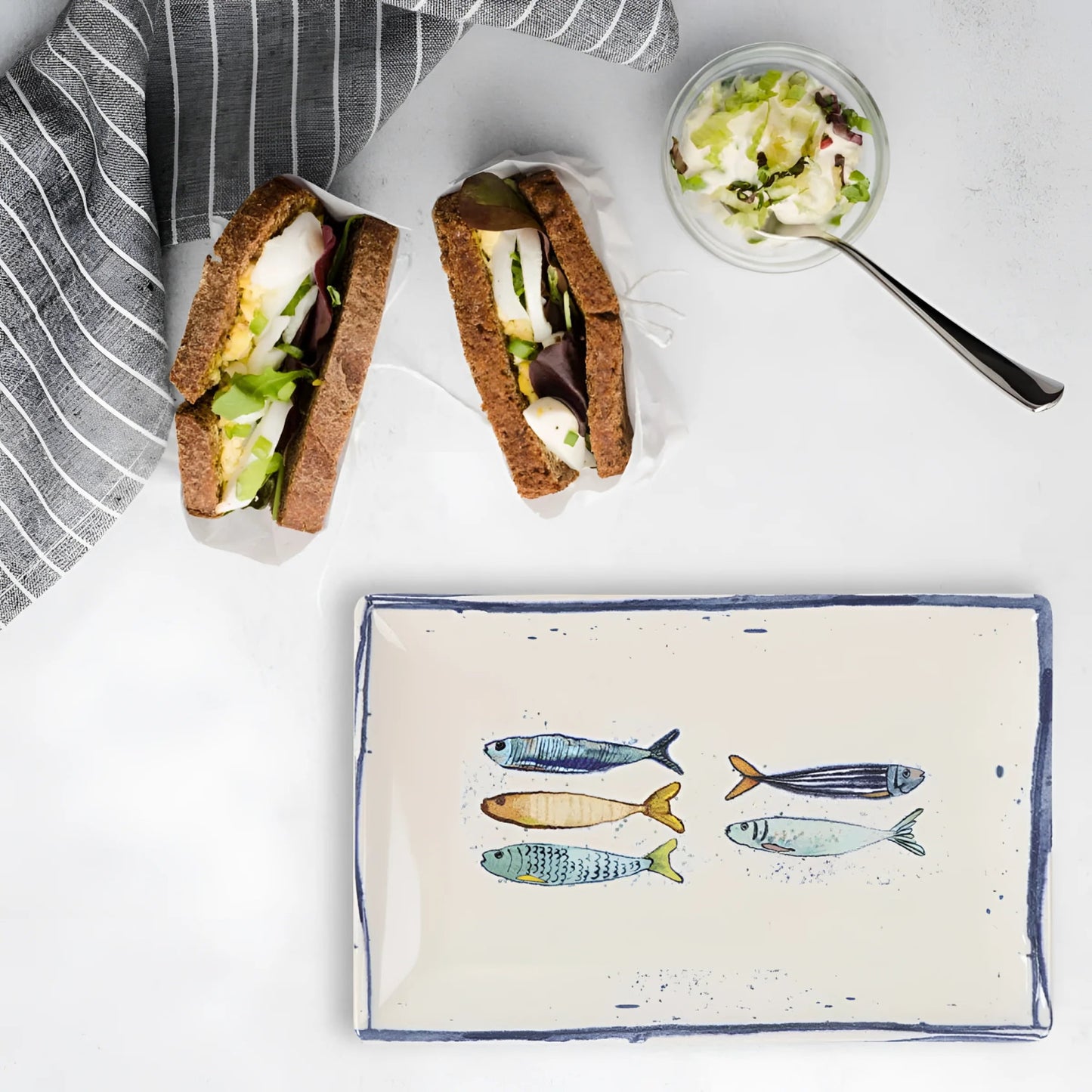 Two hearty sandwiches with dark bread and a side salad on Peixe rectangular tapas plate
