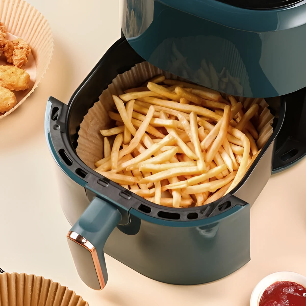 Teal air fryer with black basket of golden fries and 20cm paper liners
