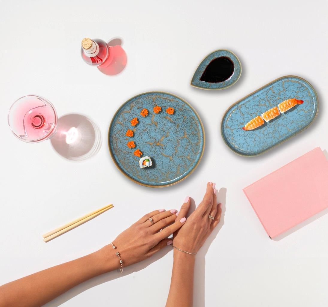 Blue ceramic dinnerware set with gold accents including a round plate, oval plate, and tear-shaped sauce dish
