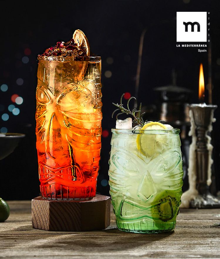 Two Tiki Highball cocktail glasses in orange and green with drinks and garnishes