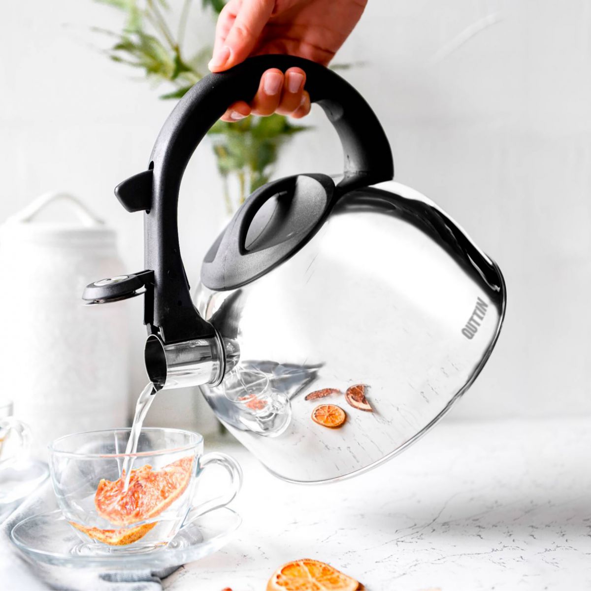 Clear glass teapot with black handle pouring water into a glass cup for 3L Stainless Steel Whistling Kettle Induction Quttin