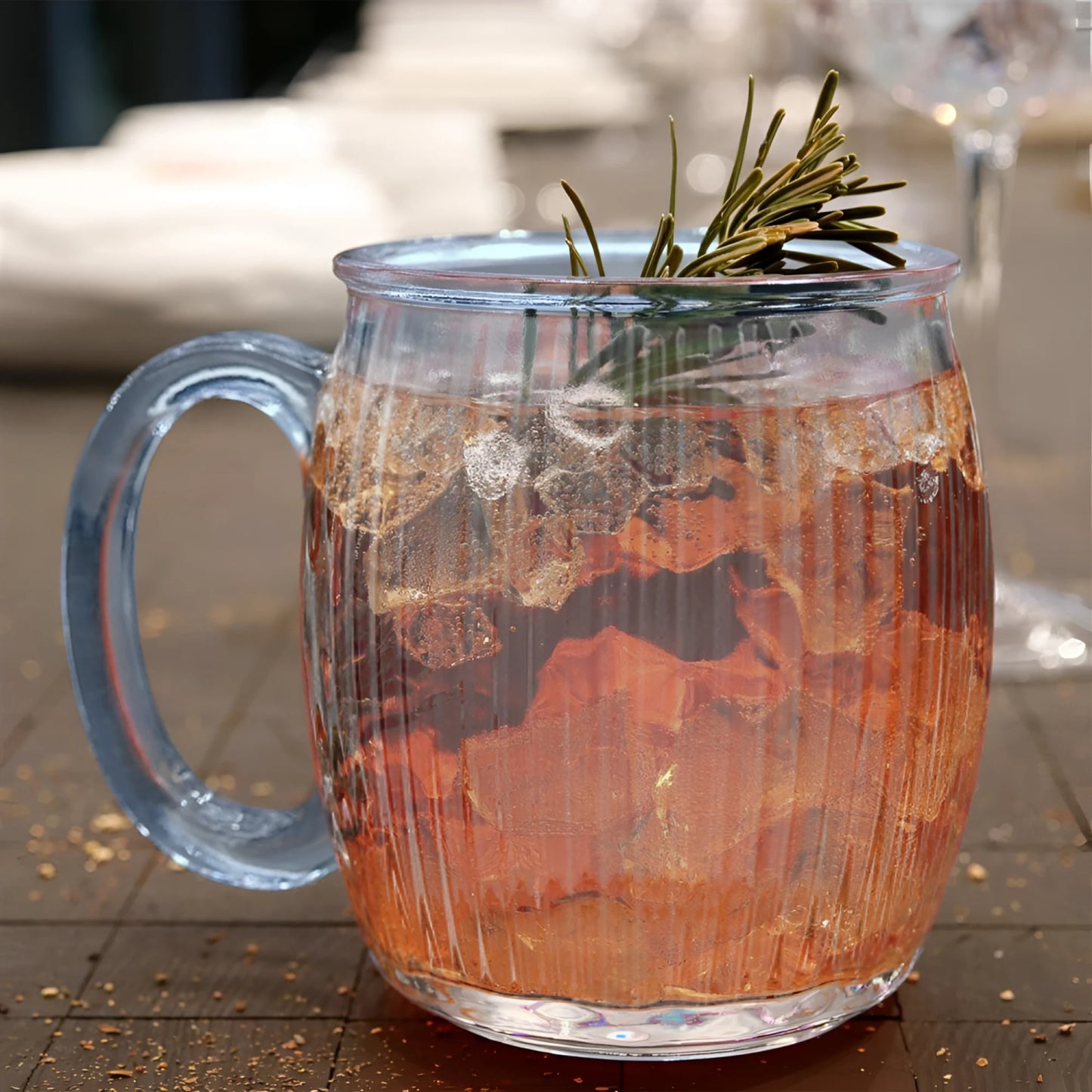Clear 350ml coloured cocktail mug with pinkish-orange iced drink and rosemary