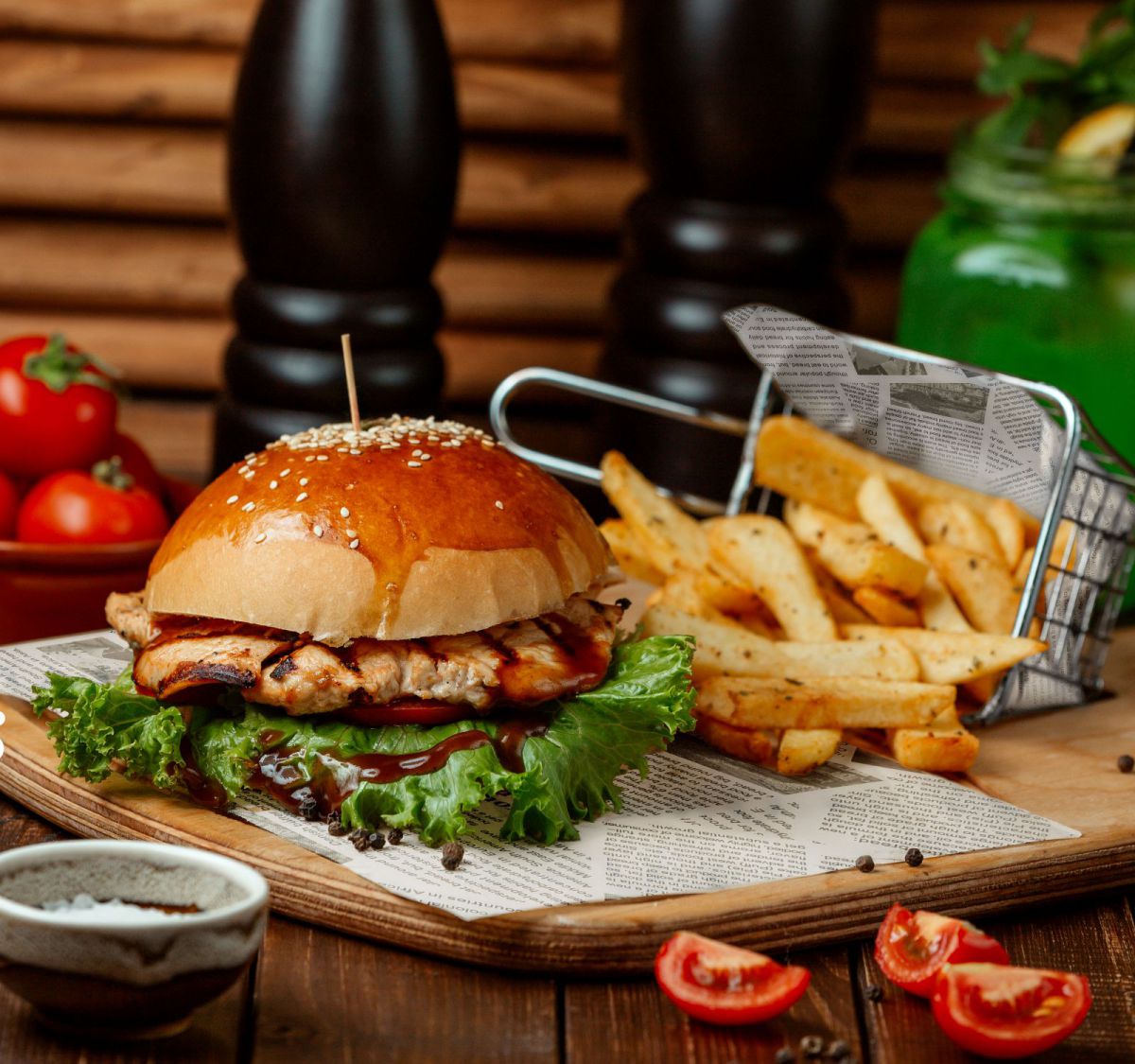 Grilled chicken burger with lettuce and sauce served with French fries on Grey Graseproof Paper