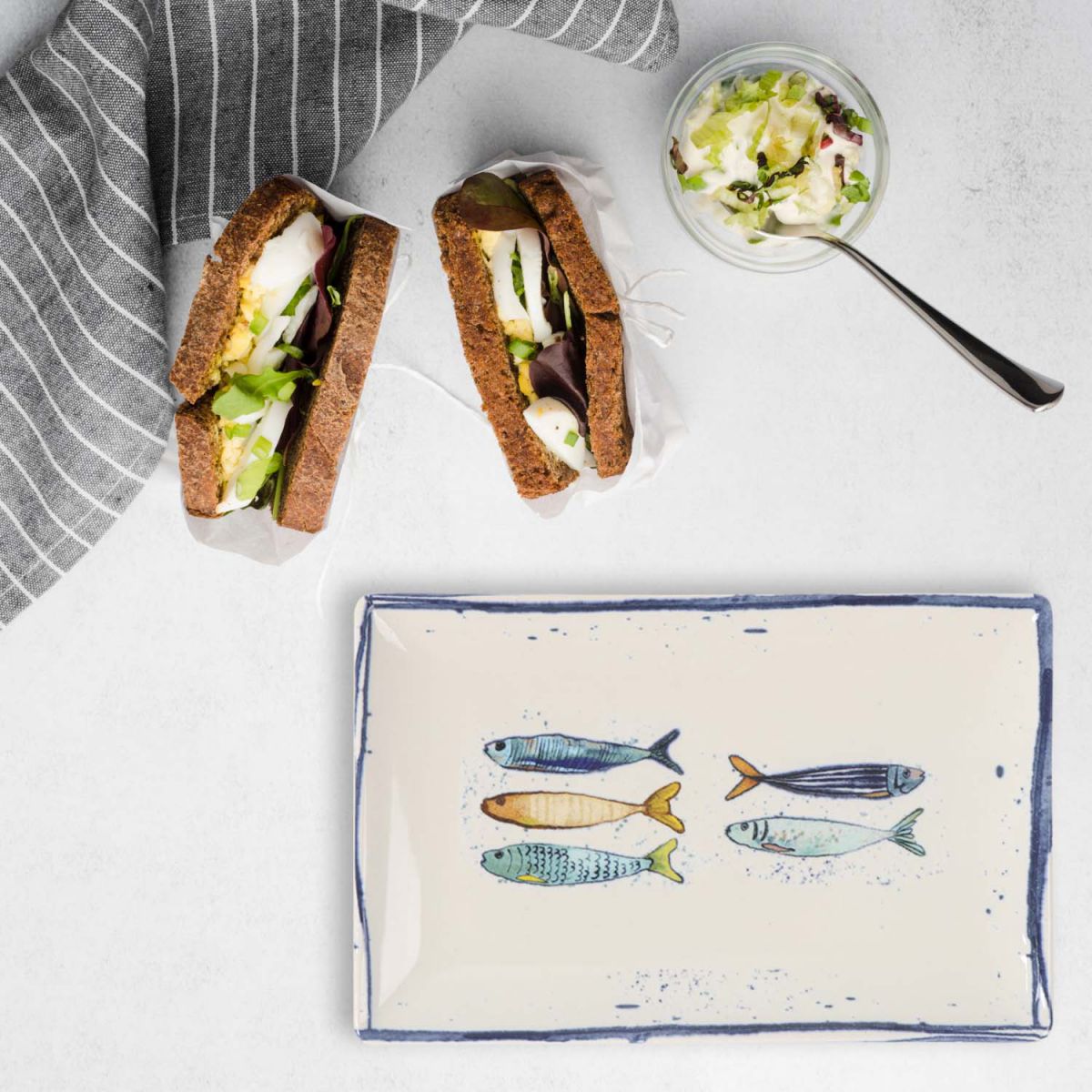 Two hearty sandwiches with dark bread and a side salad on Peixe rectangular tapas plate