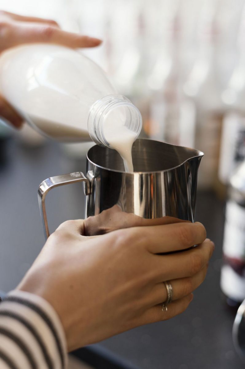 Clear plastic bottle pouring white liquid into stainless steel Milk Frothing Jug 330ml