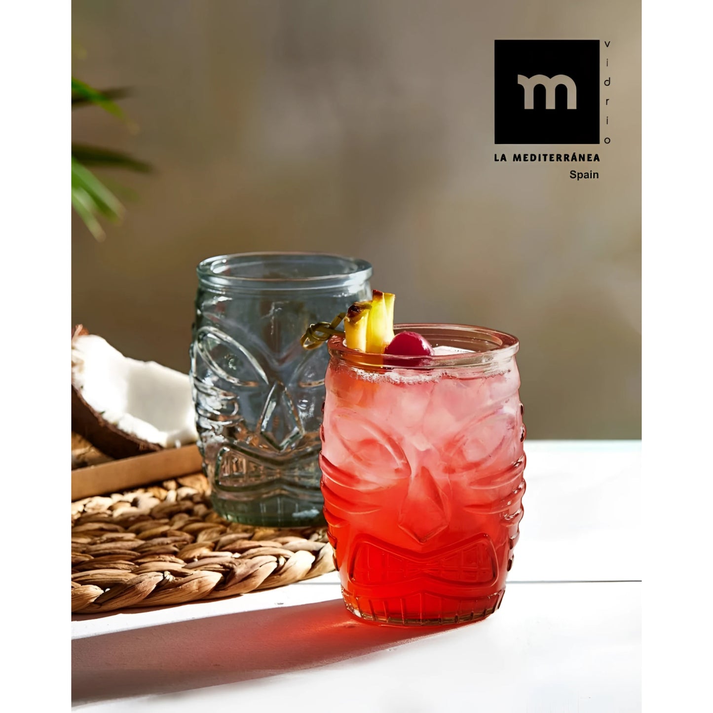 Red tiki tumbler with pink cocktail, pineapple, cherry garnish